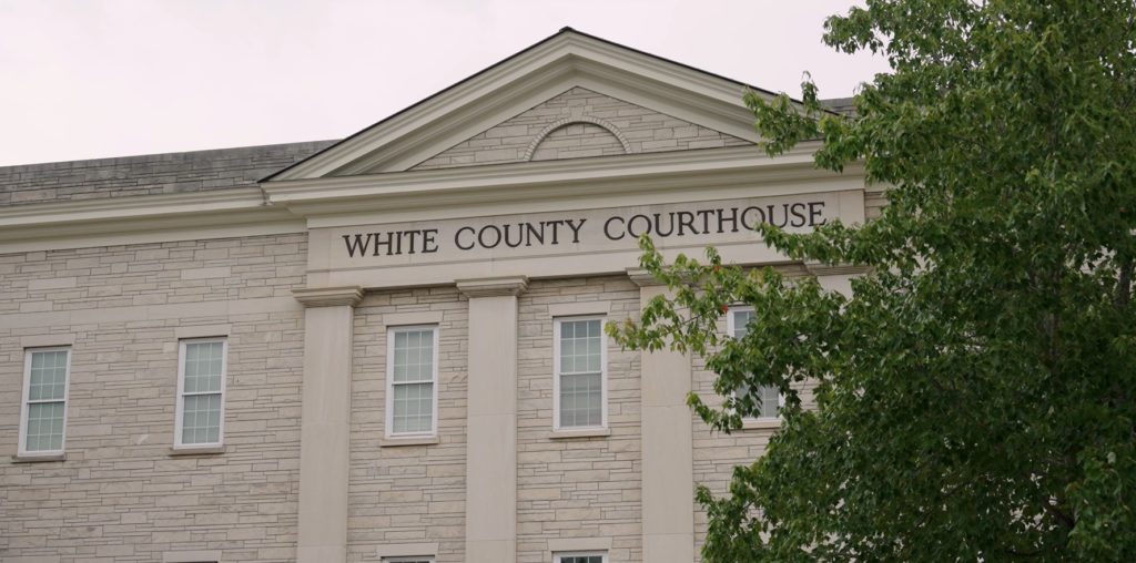 Image of White County Courthouse. A large, white courthouse with a tree on the right side of the image.